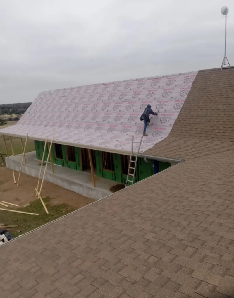Worker preparing underlayment for a metal roof installation in Ward